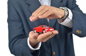 Businessman holding a toy car on his hand
